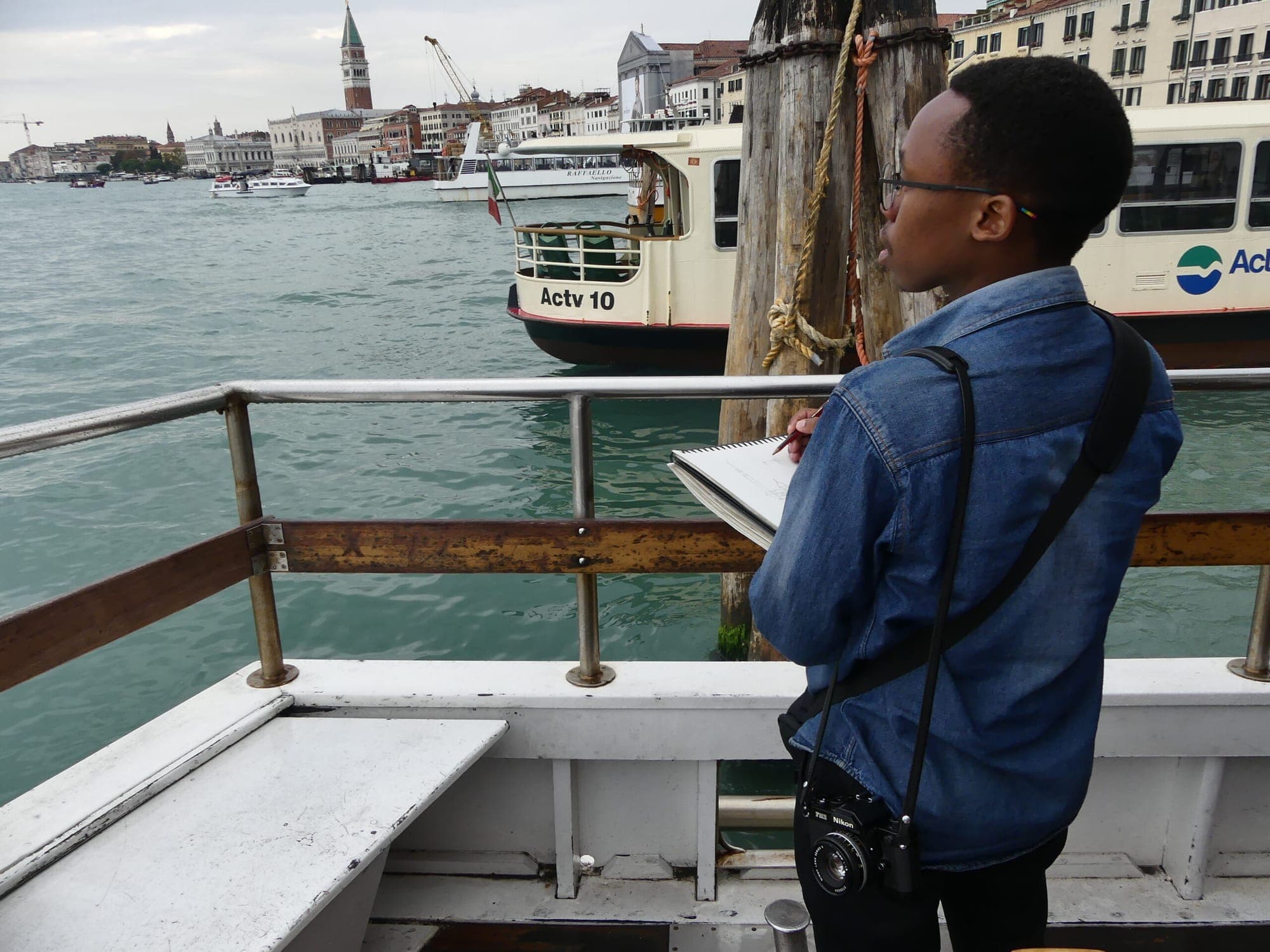A Kenyan student sketching on a boat in Venice, Italy
