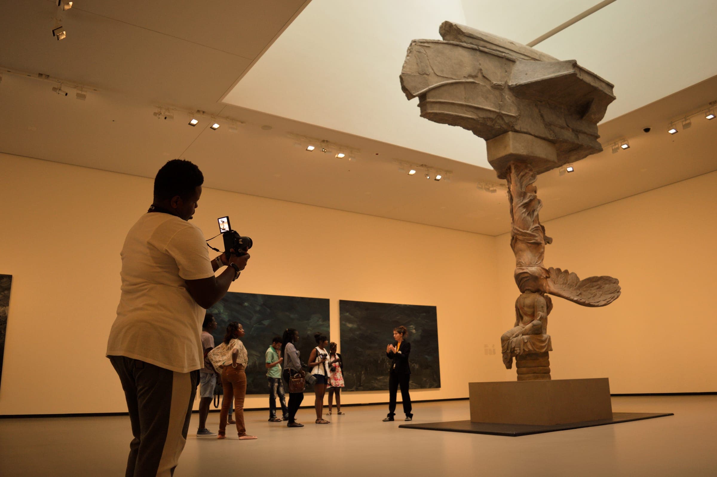 A student photographs a sculpture in a contemporary art gallery