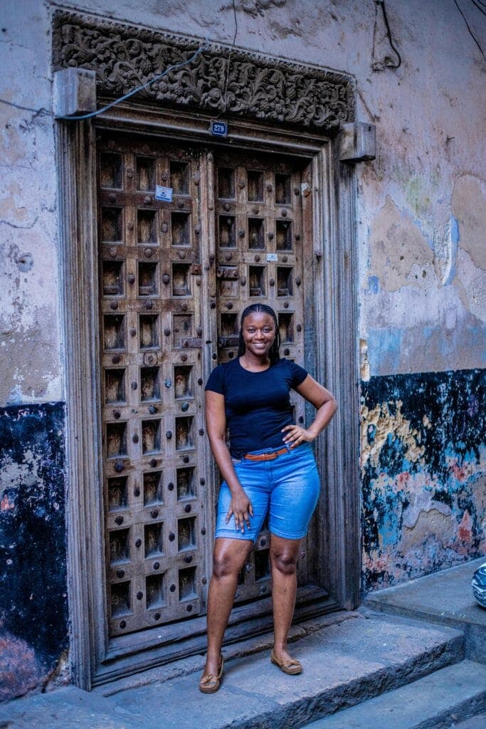 A traveller standing in front of a carved Swahili door in Zanzibar