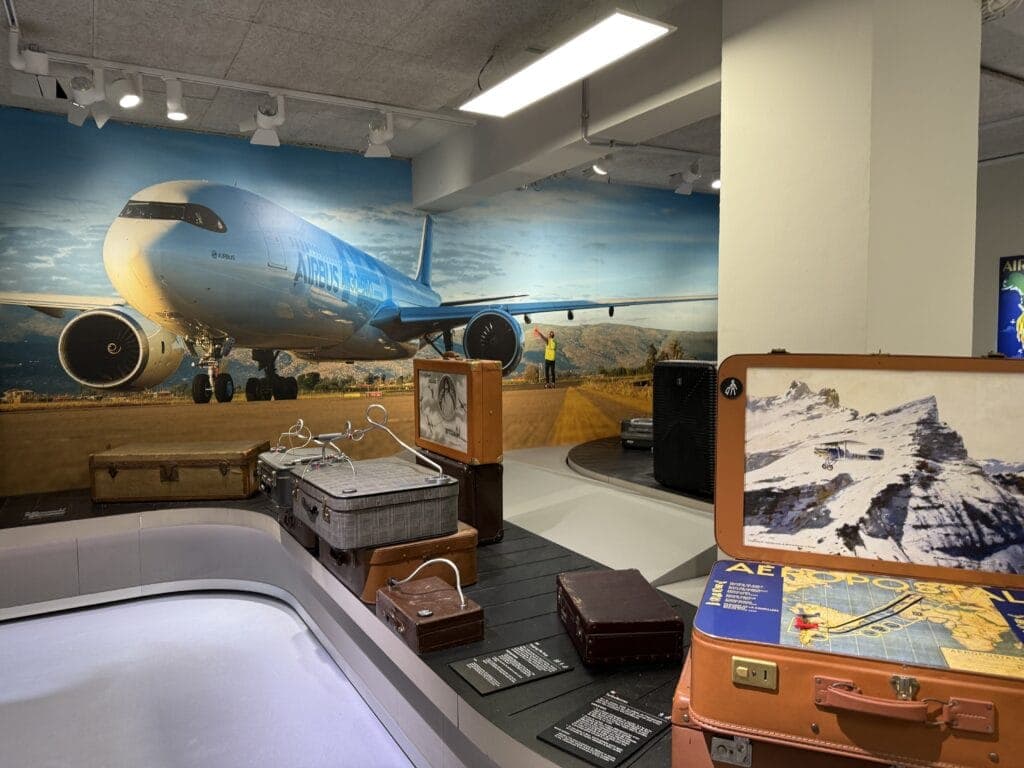 An aviation gallery with a mural of an airliner and a display of vintage suitcases