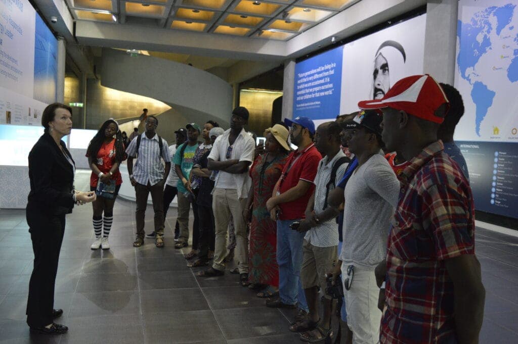 A guide briefing a student group in an exhibition hall in the United Arab Emirates